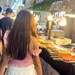 back of a teenage girl and boy in a food market in Bangkok Thailand