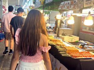 back of a teenage girl and boy in a food market in Bangkok Thailand