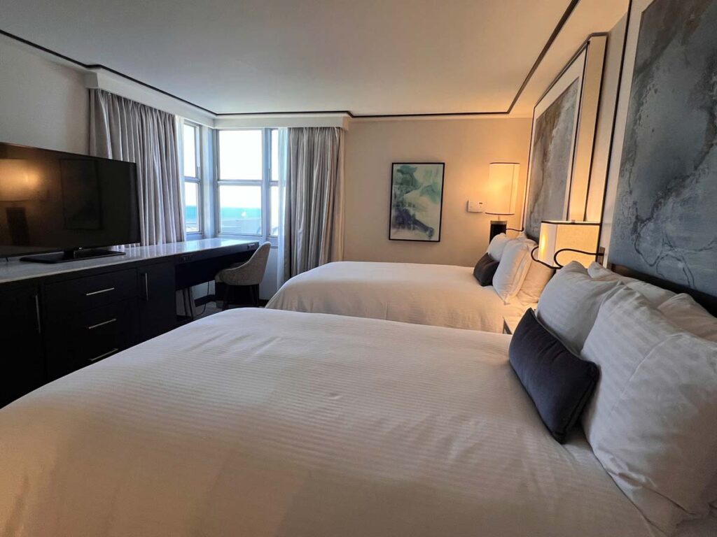 Elegant bedroom in a Loews Miami Beach Hotel suite with two double beds and an ocean view.