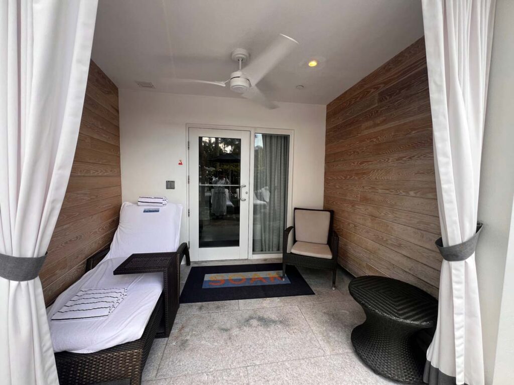 Private SOAK cabana at Loews Miami Beach Hotel with lounge chairs, cozy seating, and wooden walls, offering a relaxing space for guests.