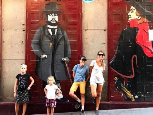 A mom and her three kids stand in front of a street art mural in Madrid.